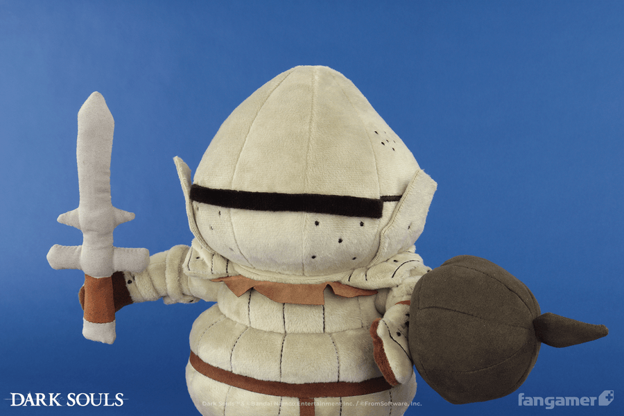 The Siegmeyer plush photographed against a blue background, holding its magnetic sword plush in one hand and its elastic-banded plush shield in the other.  - Siegmeyer Plush - DARK SOULS